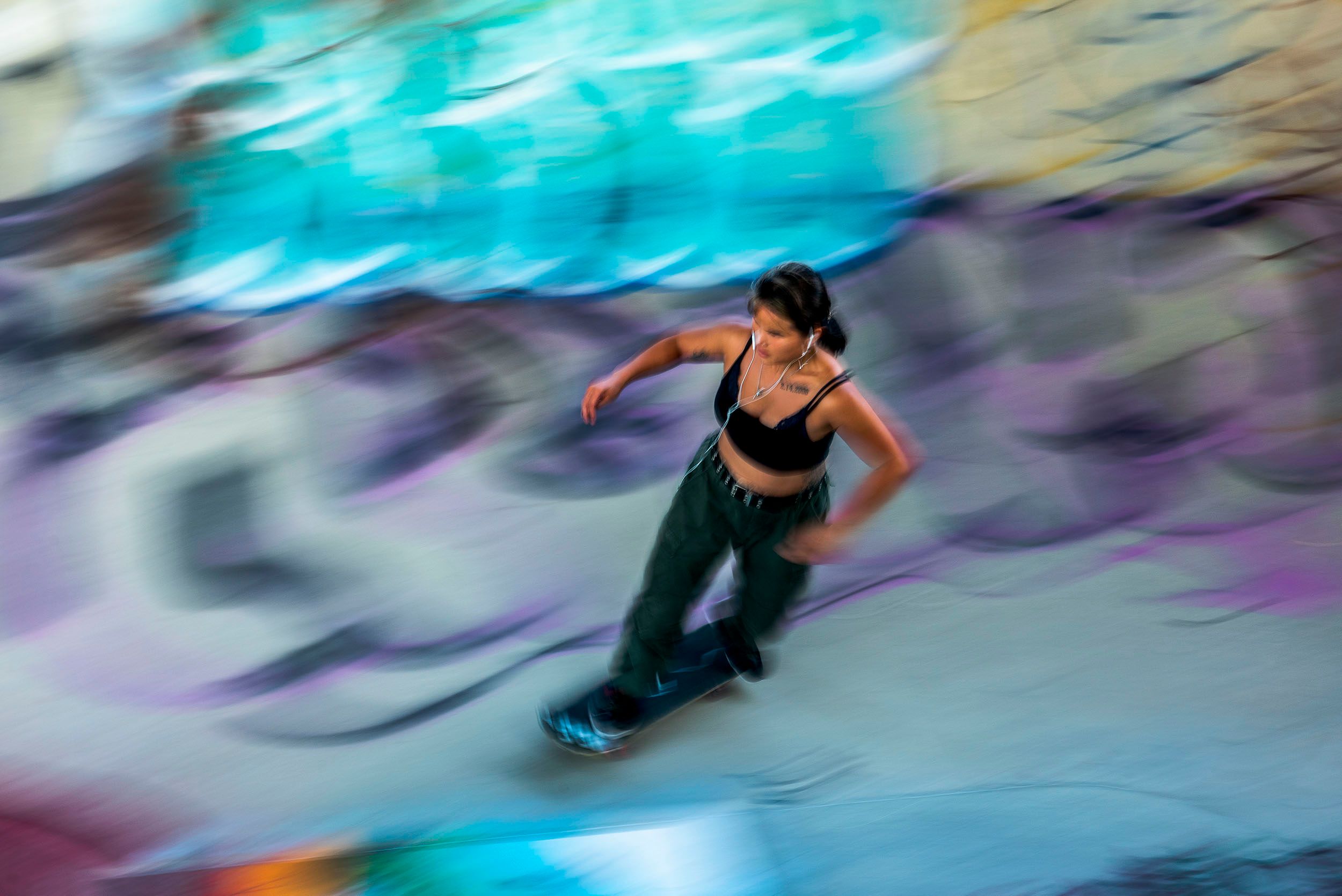 Horizontal color motion blur photograph of Katie a skateboarder doing a practice run at the Lynch Family Skateboard Park. Cambridge, MA Speed and balance
