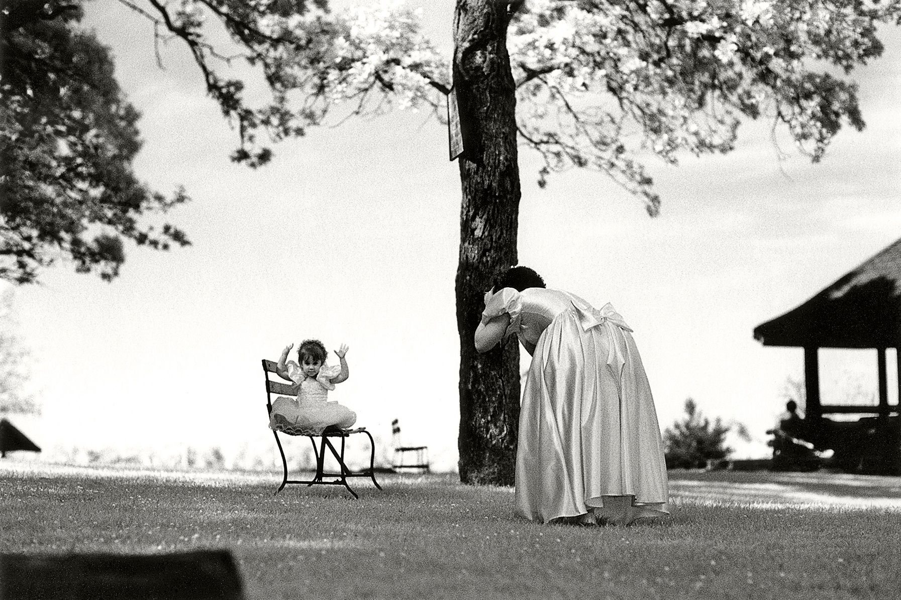 A flower girl becomes the subject of a photograph by a bridesmaid, during a wedding photography outing at Manor Park in Larchmont, New York. 1girlwaves