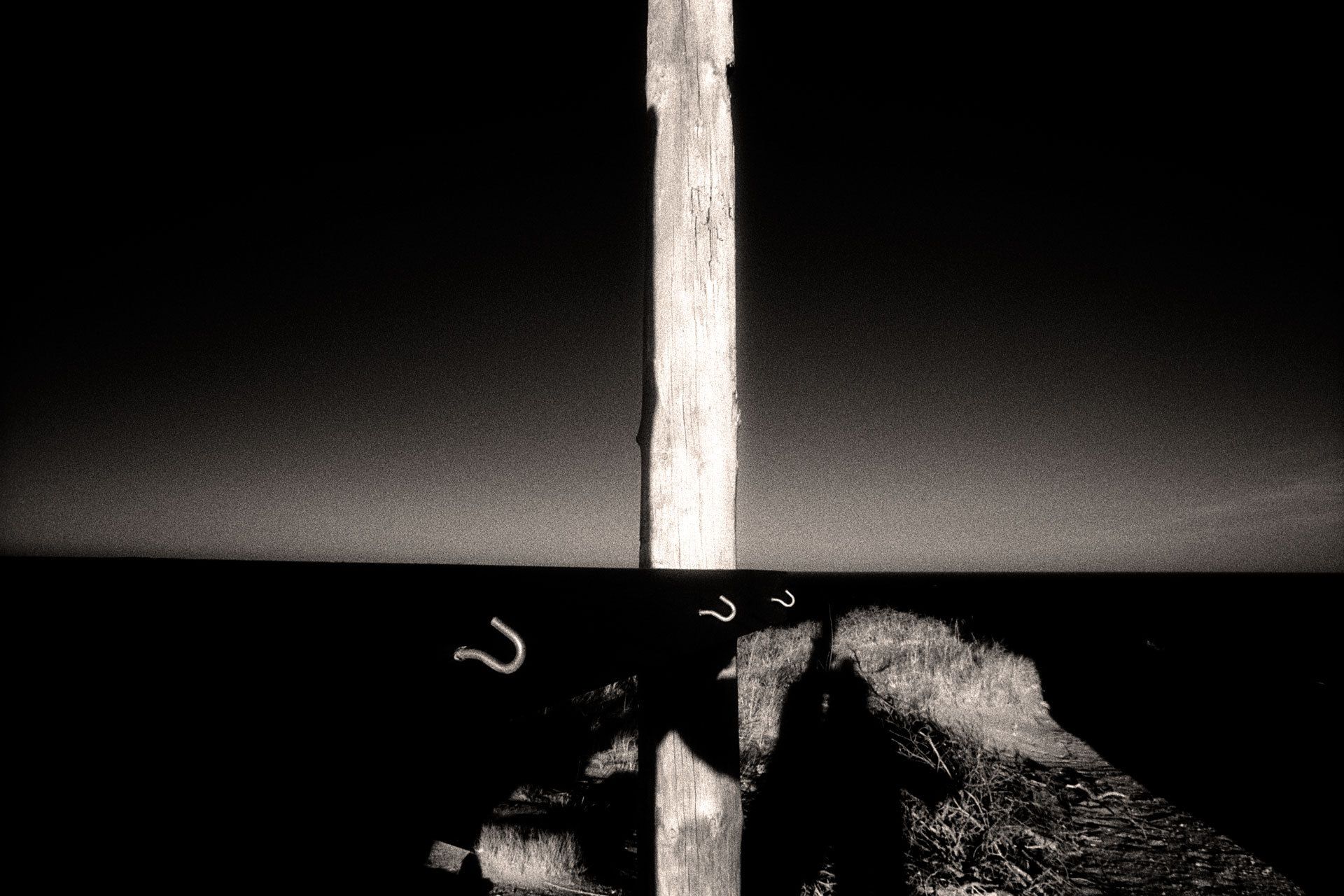 Created on a frigid winter day somewhere on Cape Cod, this photograph of a clothesline structure was one of my first infrared images in which the result was exactly how I had previsualized it--with the hooks suspended in space and receding into the distance. I also knew that because the wooden board to which the hooks were attached was in shadow, it would merge in tone with the distant blue ocean, which was itself darkened with a red filter. I lined up the board and ocean to form a single horizon, anticipating that the graduated sky would produce the feeling of a rising or setting sun. 1hooks_final