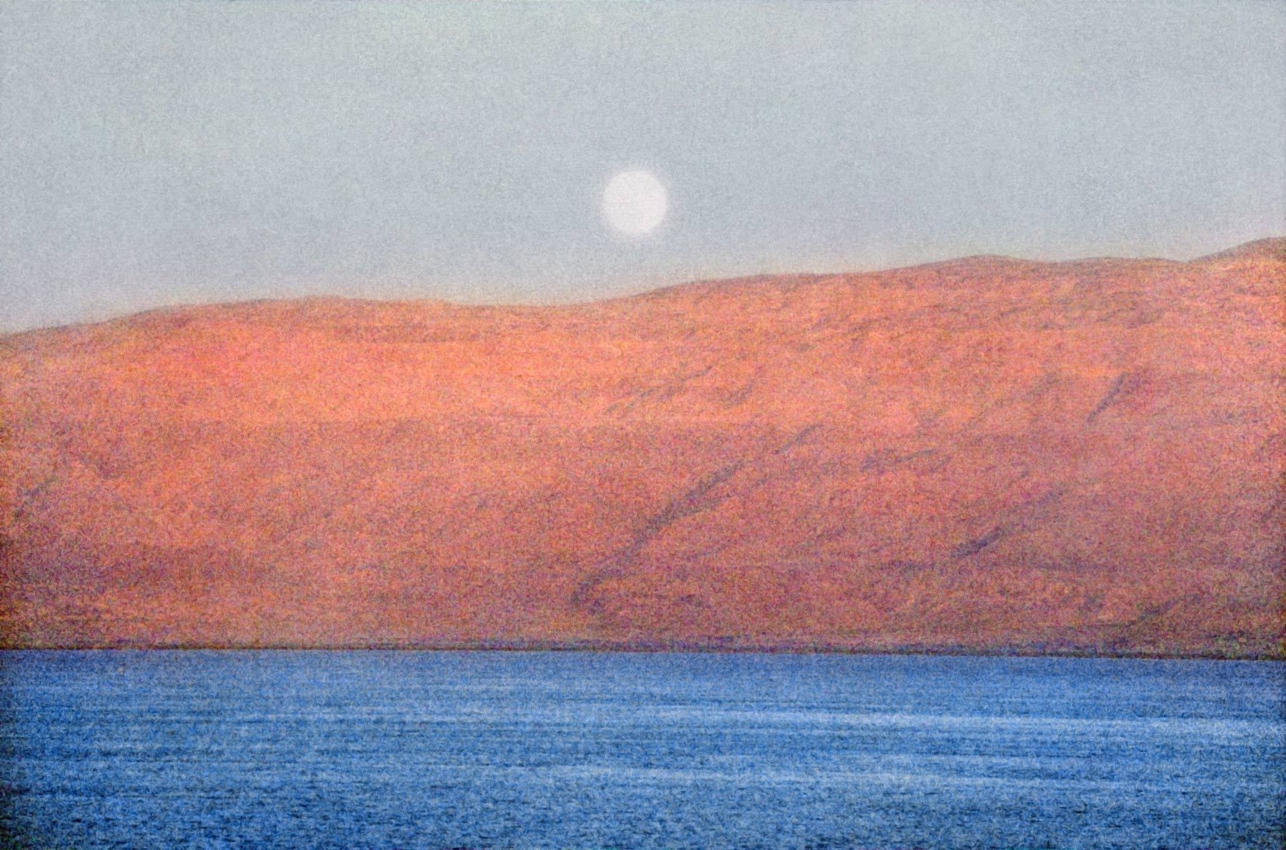 Creased, treeless mountains on the Jordanian side of the Dead Sea turn pink at sunset, as a full moon rises above them. Moonrise over Jordan