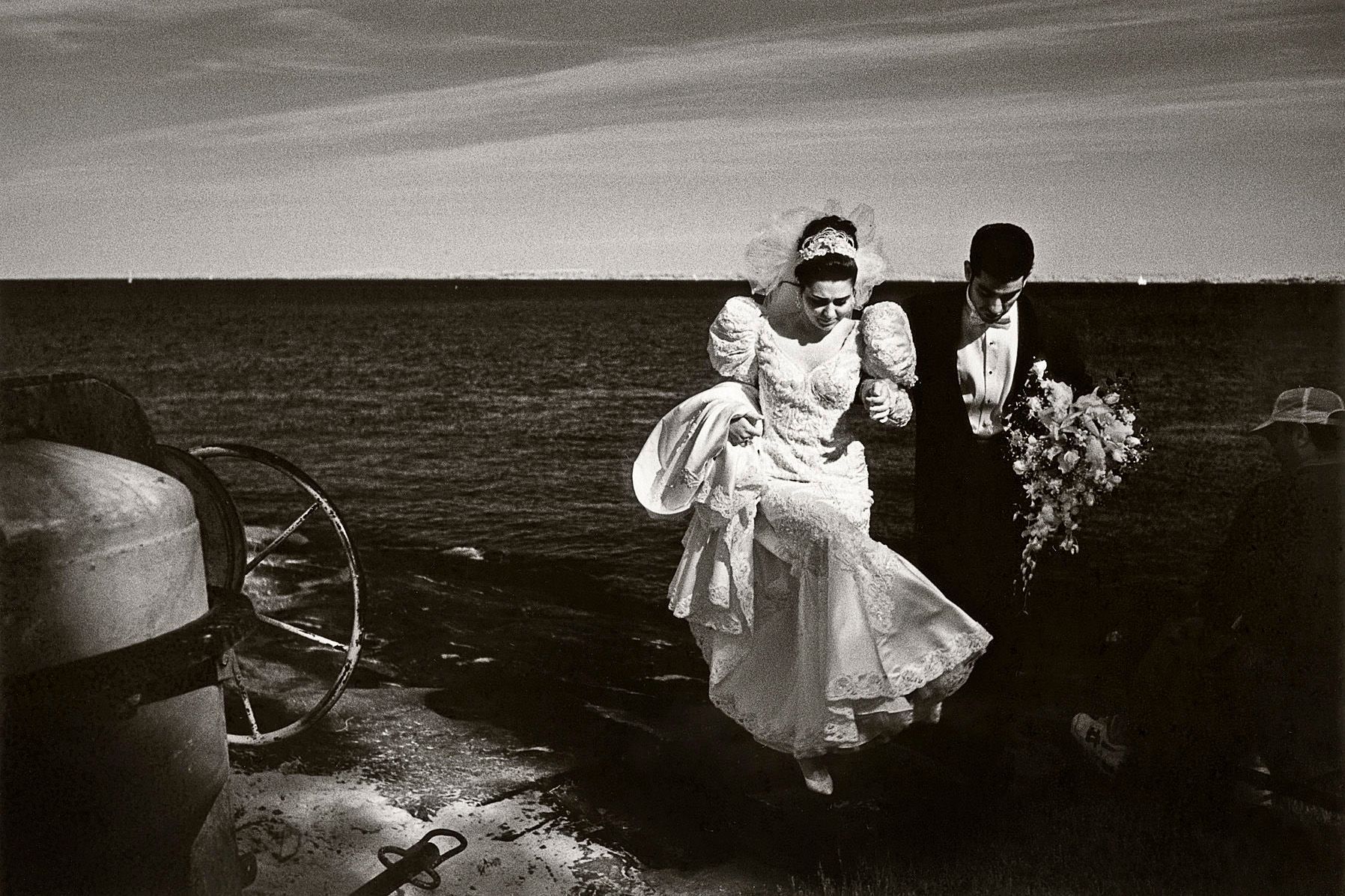 Man and wife emerge from the Long Island Sound after a wedding photography shoot, on the rocks of Manor Park in Larchmont, New York. 1couple