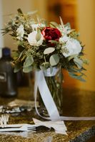 Bride bouquet in glass vase with white ribbon