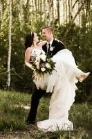 Groom carrying bride on mountain with her flowers. 