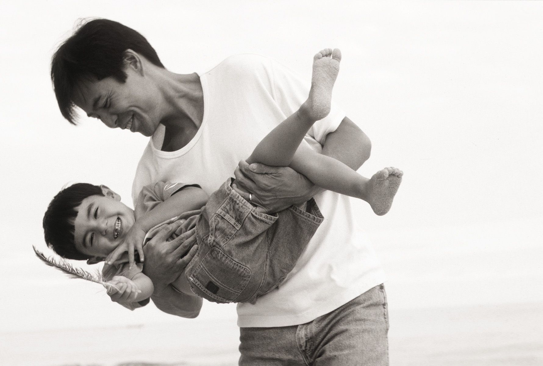 asian father holding his 8 year old son at the beach Asian father and son playing on the beach
