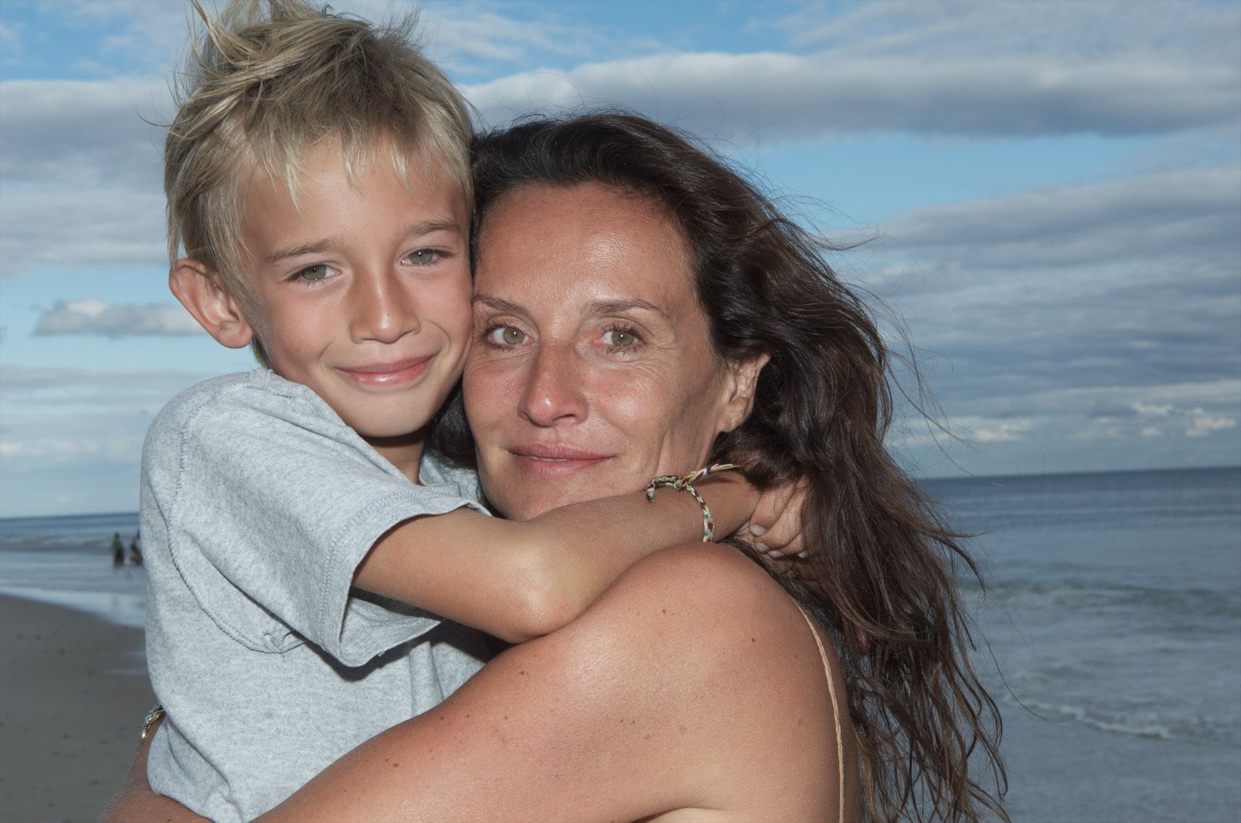 Mom with long brown hair hugging her 10 year old son at the beach pictures mother and son at the beach