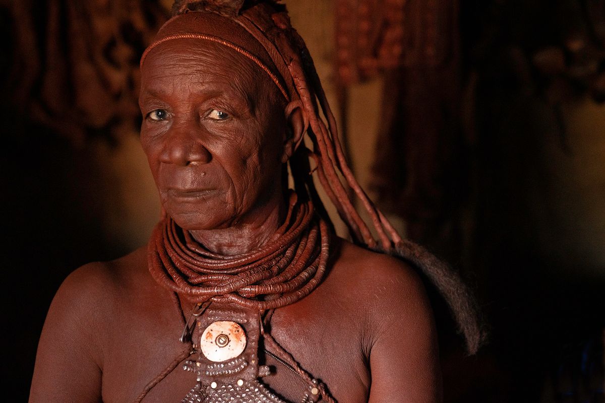 As water is scarce they use a mixture of pastes on both their bodies and hair. Elderly woman in her hut