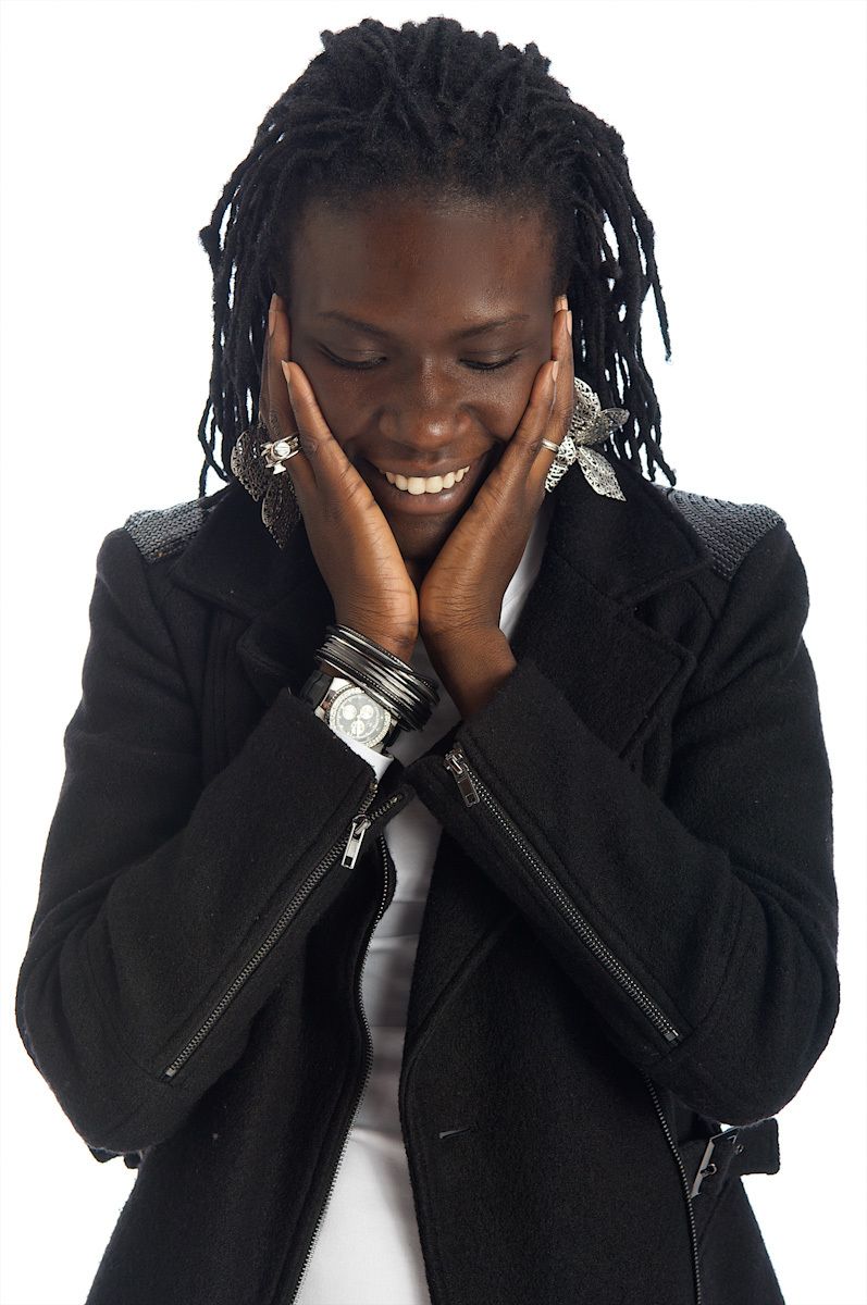 hip black woman dressed in black and wearing silver jewlery looking down and smiling hip black woman smiling