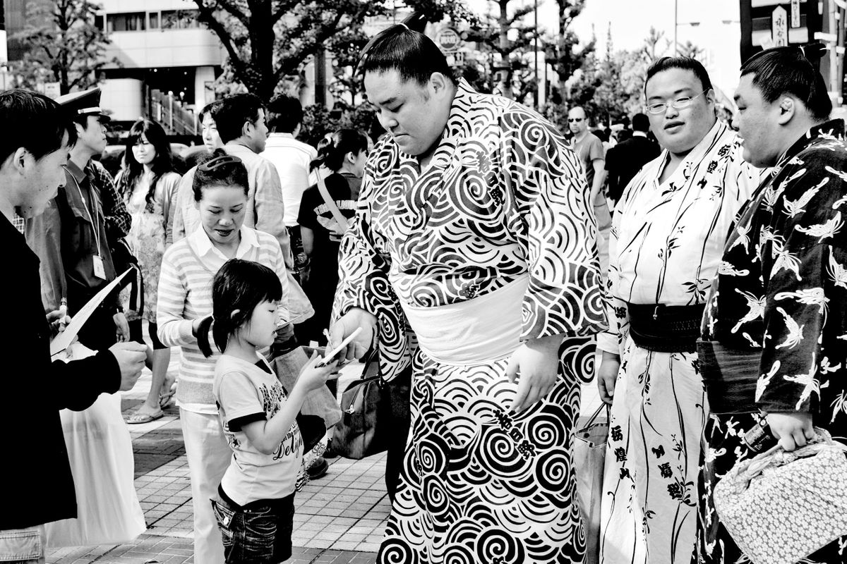 Sumo wrestlers sign autographs before a tournament. Machida, Tokyo, Japan