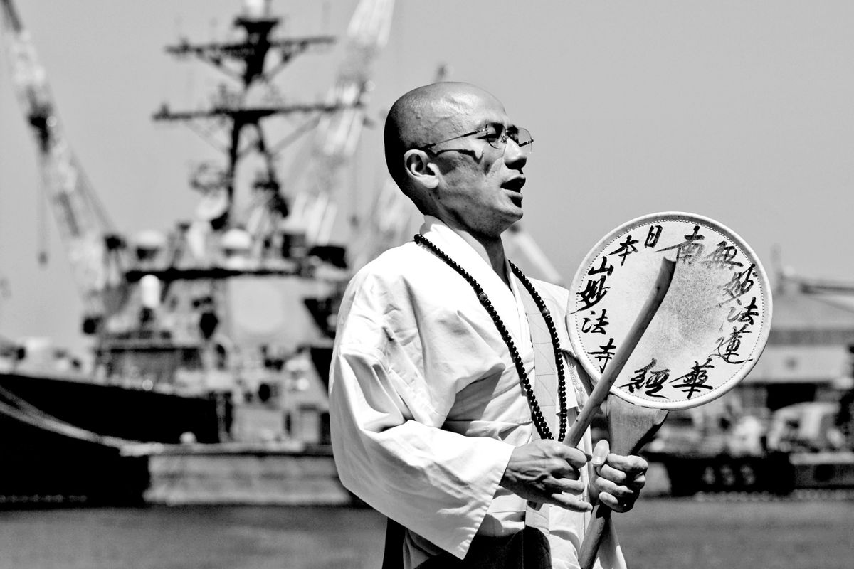 A Buddhist Monk chants alongside the US Fleet Naval Base. Yokosuka, Kanagawa, Japan