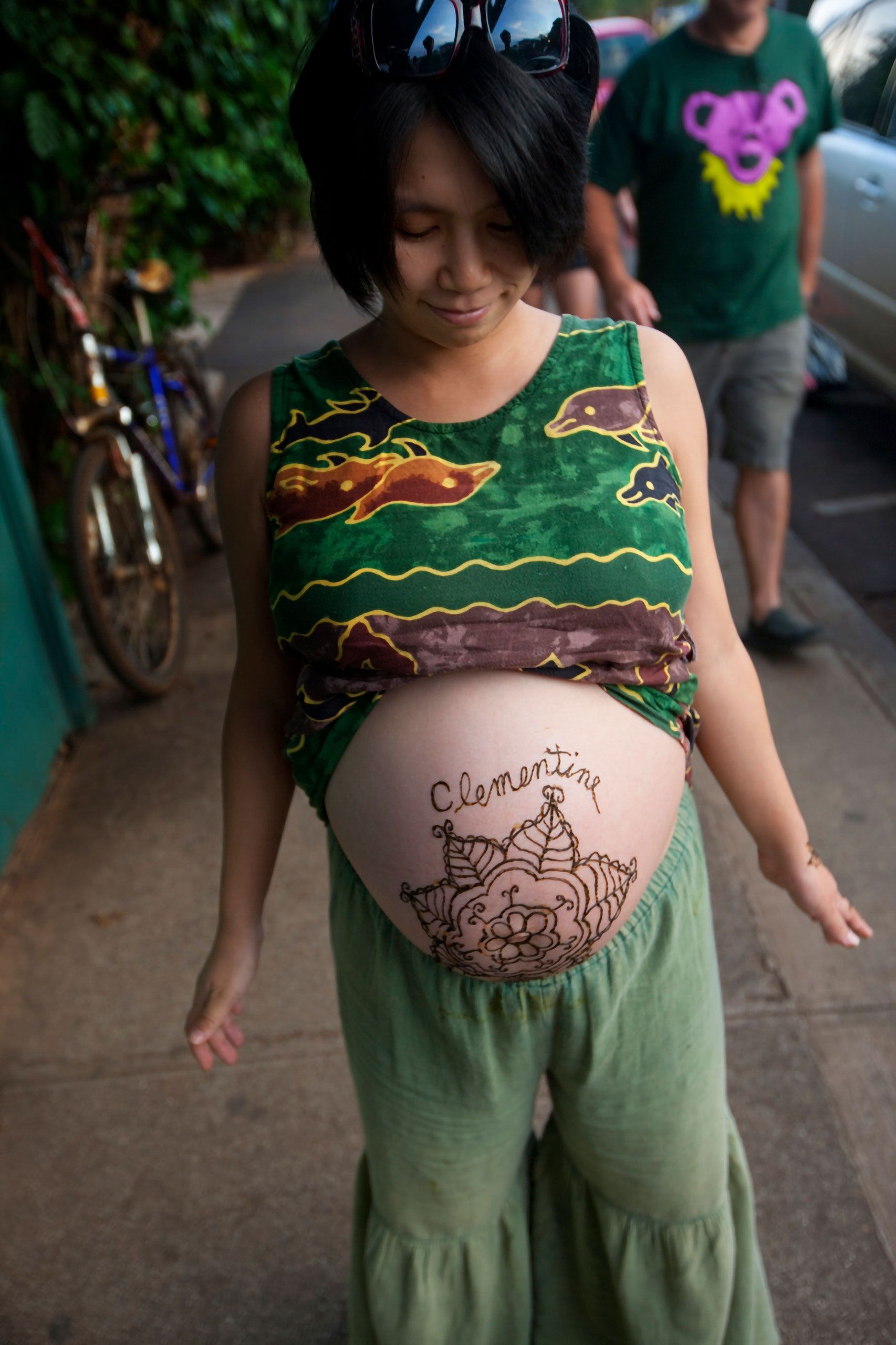 Clementine is pregnant with a big henna tattoo  on sidewalk outside Mana Foods maui Hawaii