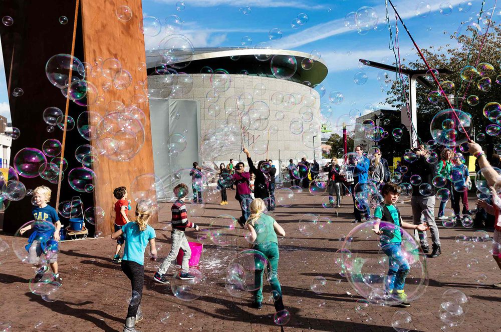 Kids blowing soap bubbles outside a museum in Amsterdam  joy