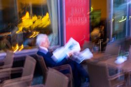 Man reading newspaper in Berlin sidewalk caffe