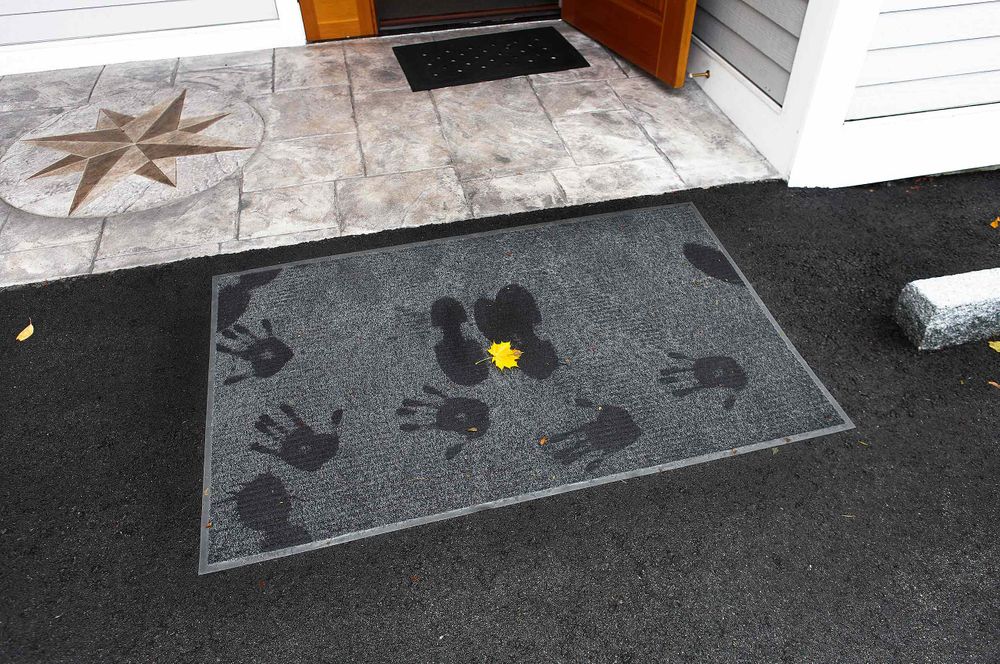 Footprints and handprints on doormat at Warren Roos Photo studio on South Portland Maine compass rose in background