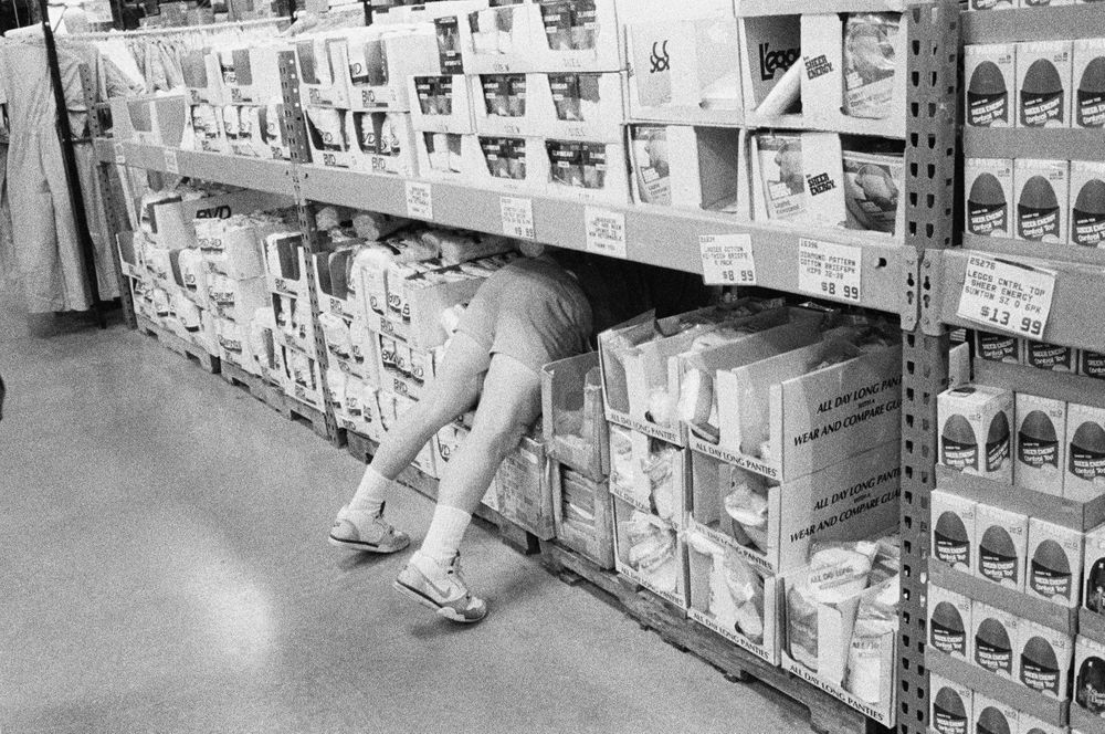 Man in store diving in for something B&W street photography 1970 nineteen  seventies