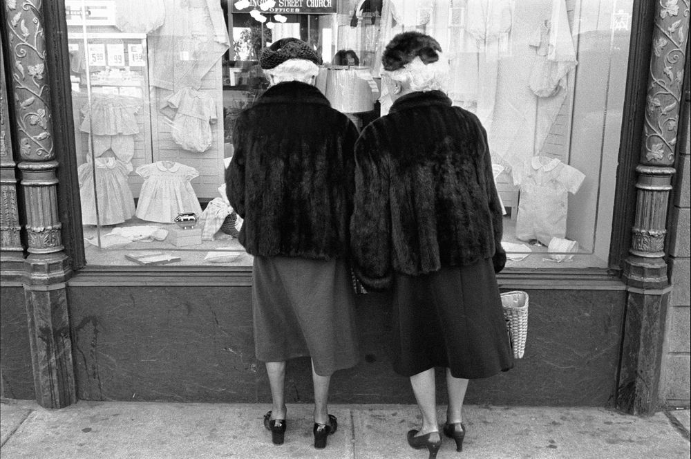 ladies in mink look at baby clothing in NYC B&W street photography 1970 nineteen  seventies
