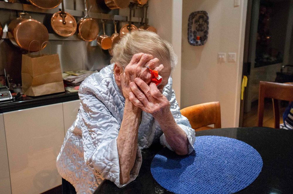 elderly woman hiding from camera copper pots lkitchen