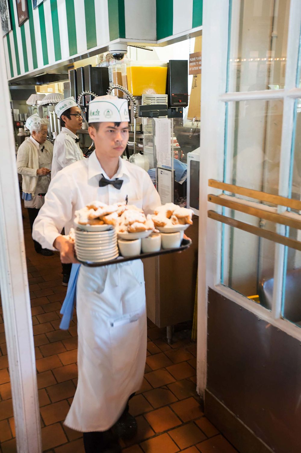 waiter with coffee and beignets at  Cafe Du Monde French Market