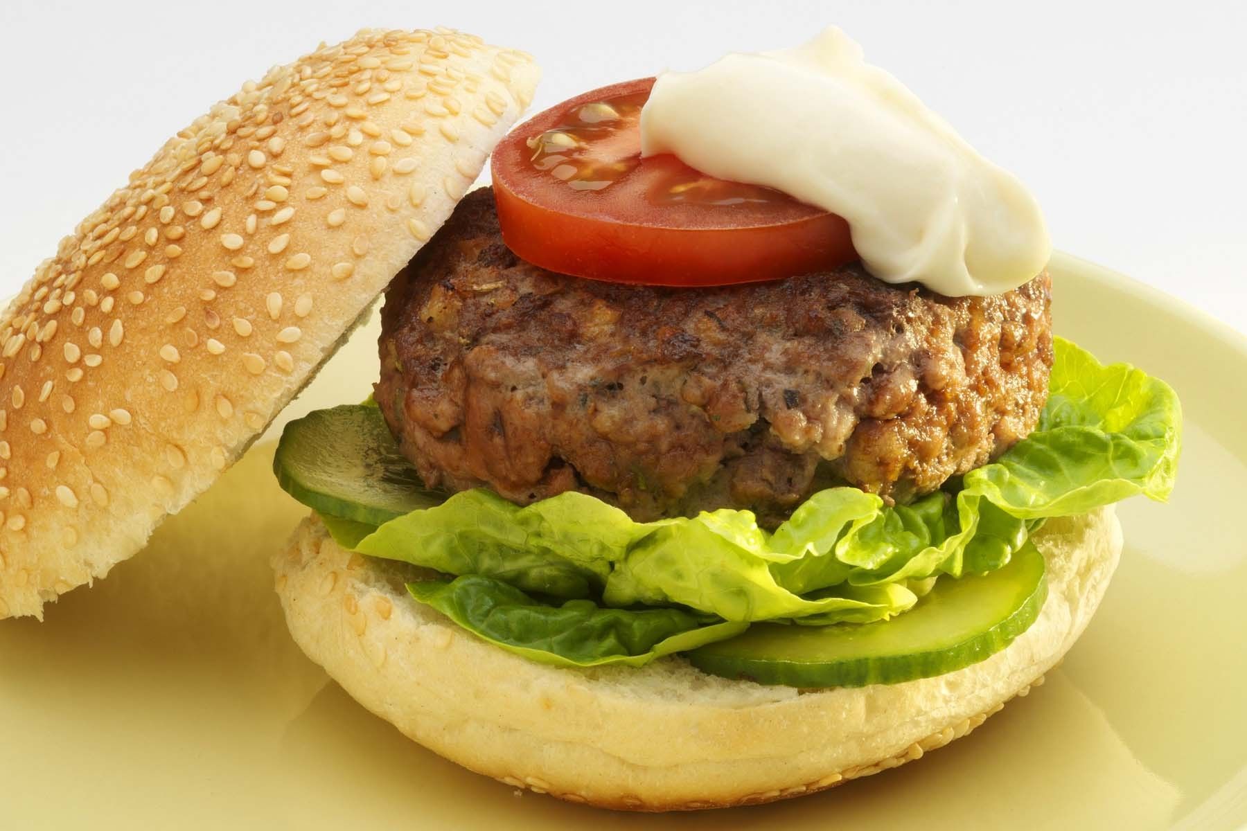 Burger in bun with salad and mayonnaise.