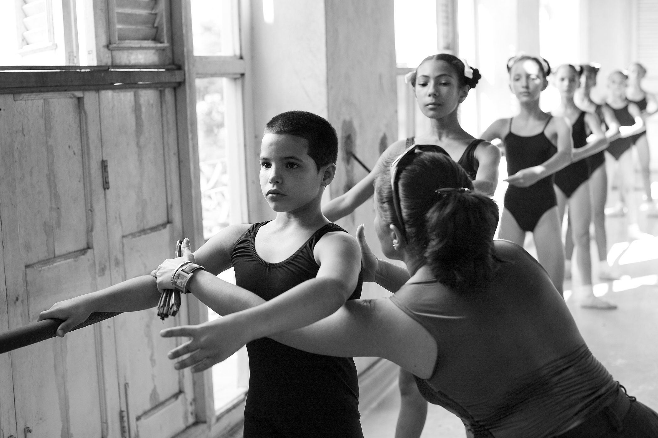 a ballet instructer at el escuela nacional cubana de ballet in havana corrects a young dancer during class. dancers from the largest ballet school in the world often enter lucrative careers with the national ballet of cuba and performing for tourists at several of the cities historic nightclubs. CORRECTION