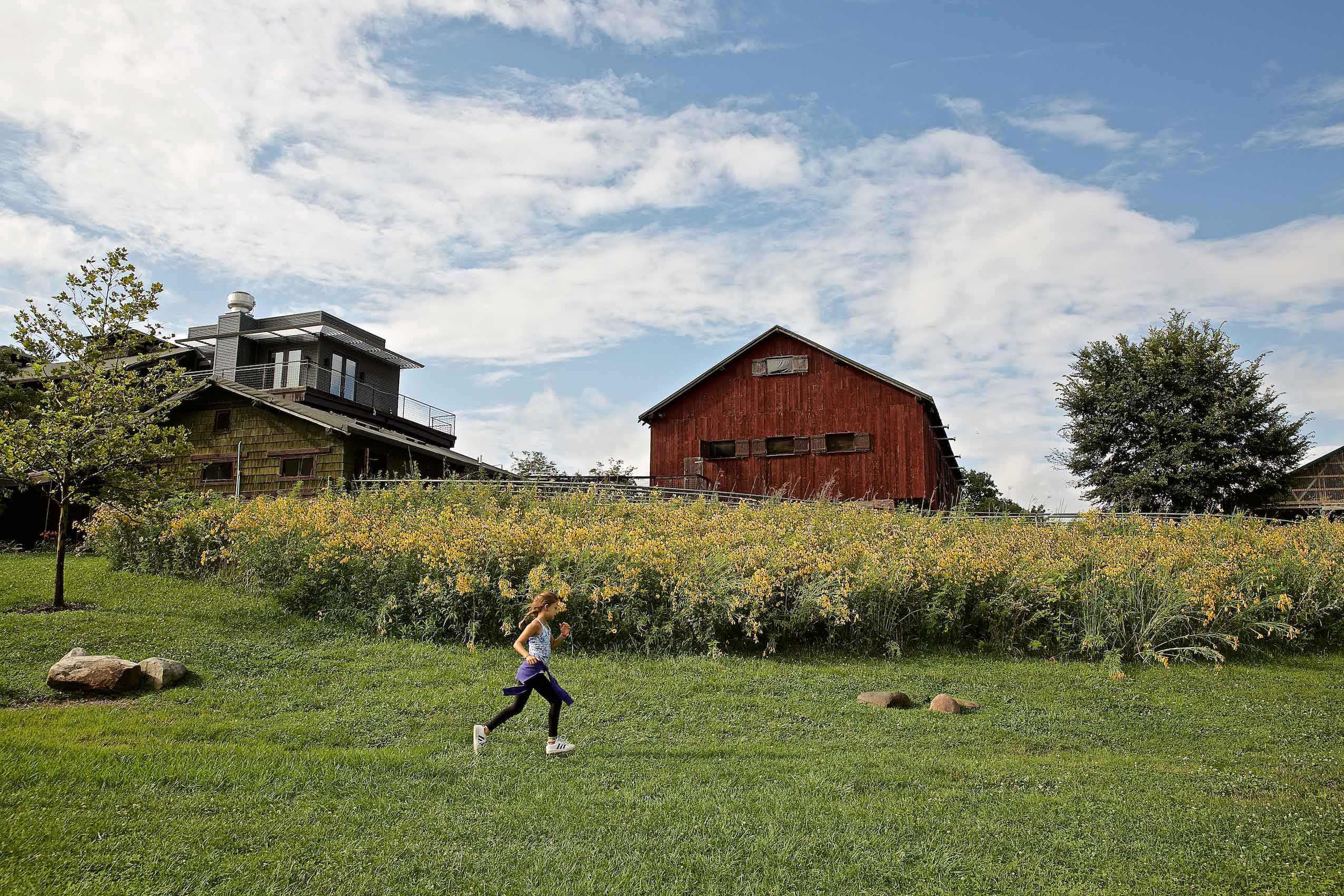 Girl Running In Front of a Red Barn