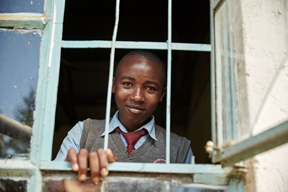 Secondary school male looking into the camera for the African Teacher Foundation: The kids were studying for a very intense, make or break exam called the KCSE examination. BoyLookingThruWindow.jpg