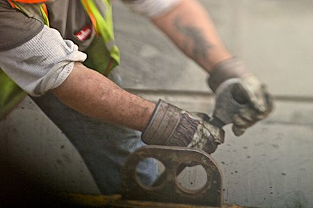 A photo of a close up of a mans gloved hands pulling on a wrench, selective focus and shallow depth of field. Closeup of man With Wrench
