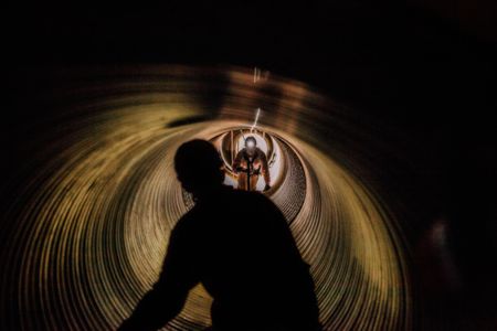 A rescue training in session inside of a tunnel. Men in protective gear and headlamps in action. Photo of Loss Control person dressed in protective fire gear, training and ready for action and to respond and mitigate a disaster as it relates to risk management in the insurance industry. Environmental portrait, and we are a industrial photographer, on location photographer & location commercial photographer. Rescue Training in a Tunnel