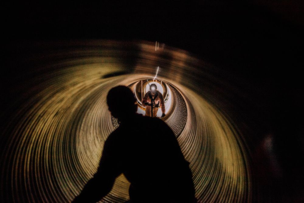 A rescue training in session inside of a tunnel. Men in protective gear and headlamps in action. Photo of Loss Control person dressed in protective fire gear, training and ready for action and to respond and mitigate a disaster as it relates to risk management in the insurance industry. Environmental portrait, and we are a industrial photographer, on location photographer & location commercial photographer. Rescue Training in a Tunnel