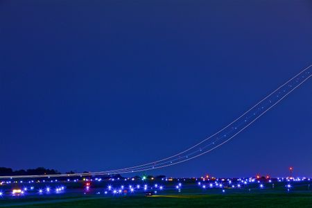 A wide photograph with a very slow shutter speed photograph of a cargo plane landing at an airport. The slow shutter speeds shows the exact trail the plane is on creating streaks through the night sky. Next stop, the other side of the world! This was a project shooting for the air cargo transportation industry. This project was amazing as an industrial photographer, on location photographer & location commercial photographer. Shallow depth of field and selective focus with slow shutter speed and some motion blur. Streaks of Airplanes in a Night Sky