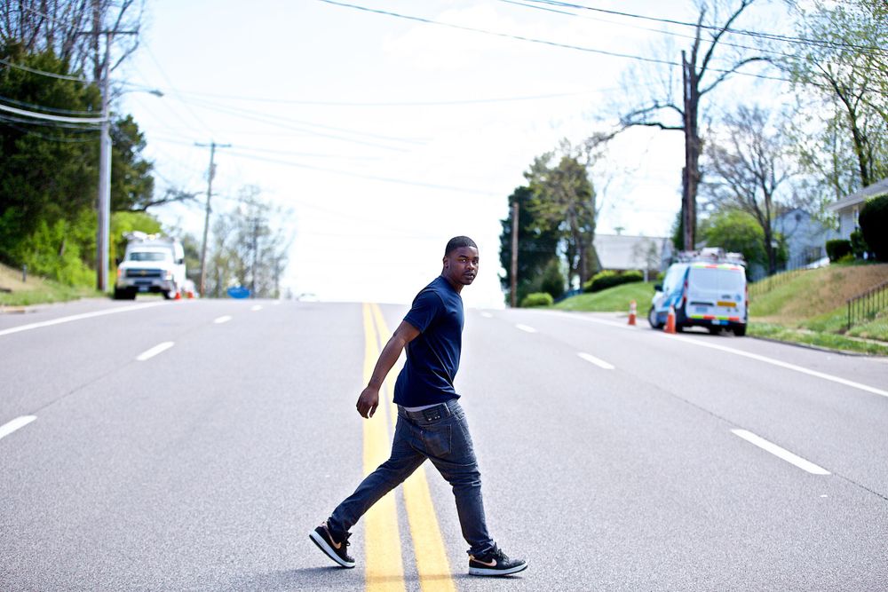Advertising photographer, on location photographer & location commercial photographer. A wide photo of a man crossing the street looking at the camera. Shot for a United Way advertising and collateral campaign. Photo of one of the many people that the United Way is assisting. Wide Photo of a Man Crossing the Street