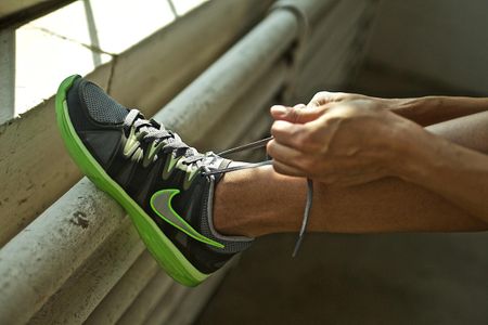 A woman, close up of her hands tying her Nike shoe. Shot with shallow depth of field and shallow focus. Nike Shoe Being Tied