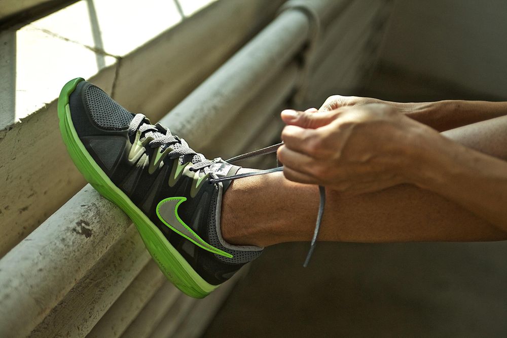 A woman, close up of her hands tying her Nike shoe. Shot with shallow depth of field and shallow focus. Nike Shoe Being Tied