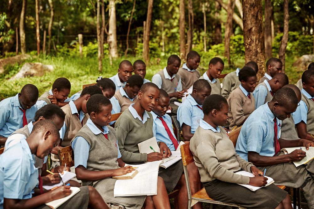 Secondary school kids at an outdoor classroom studying, while one kid looking into the camera. Outdoor Classroom closeup.jpg