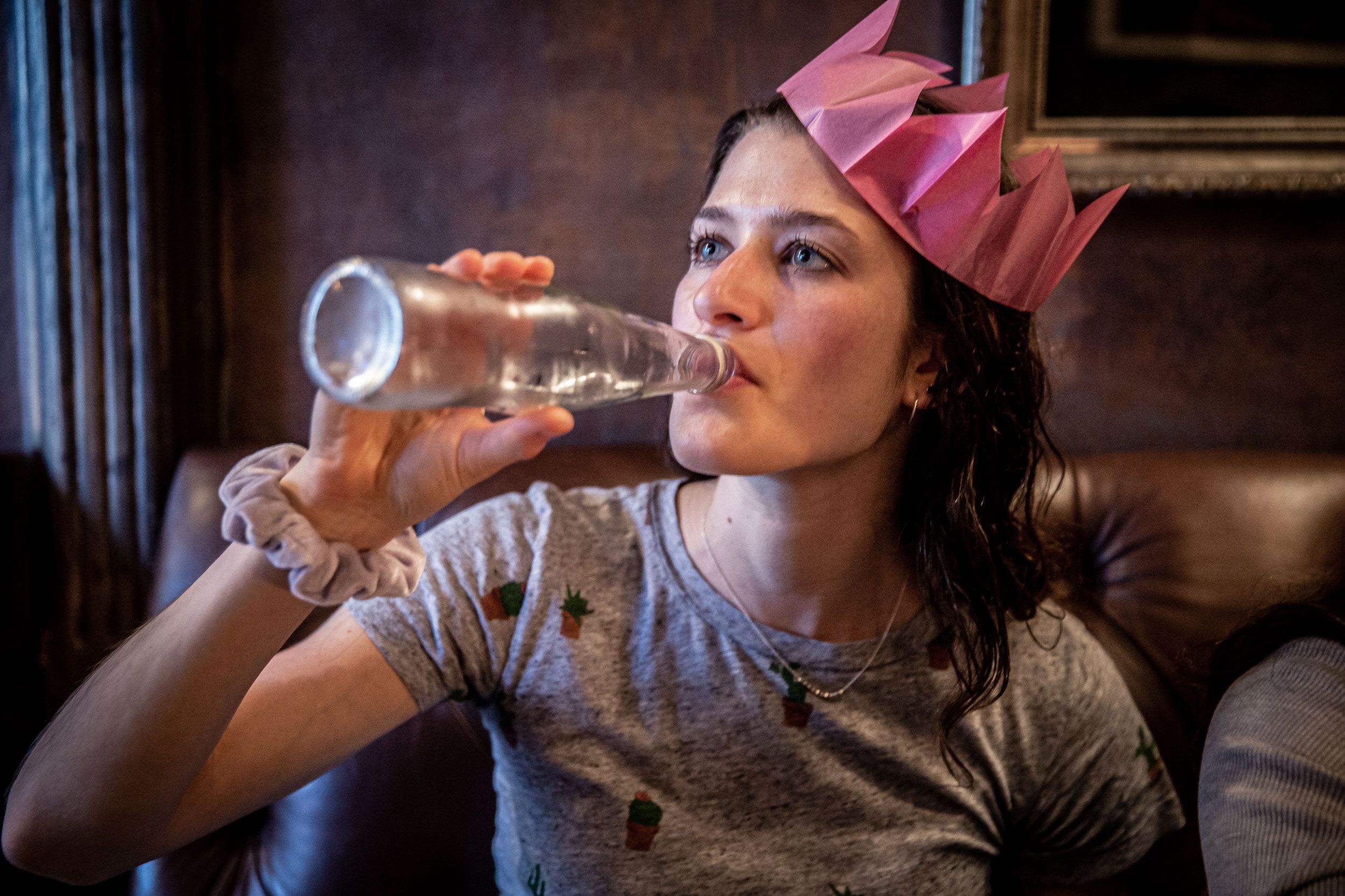 Woman with Paper Crown Finishes Drink 