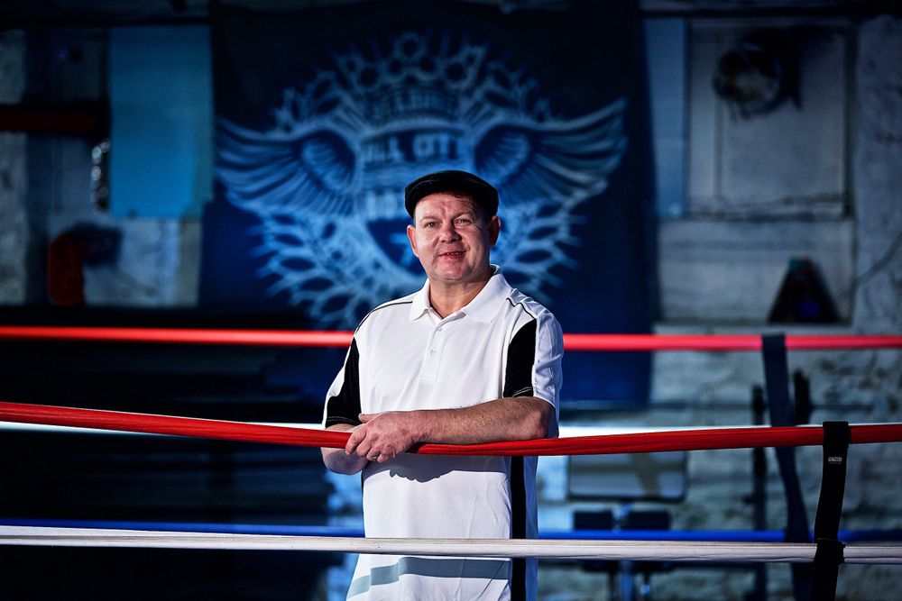 Photo of a man who used to box, standing in a boxing ring smiling, for a United Way advertising and collateral campaign. Photo of one of the many people that the United Way is assisting. Advertising photographer, on location photographer & location commercial photographer. Man in Boxing Ring