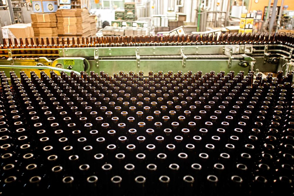 Wide photo at Schlafly Beer in St. Louis for an advertising campaign and image brand library. A wide shot of an area filled with empty beer bottles waiting to be filled.. As an industrial photographer, on location photographer & location commercial photographer this was a great project to be associated with. Production Line of Empty Beer Bottles