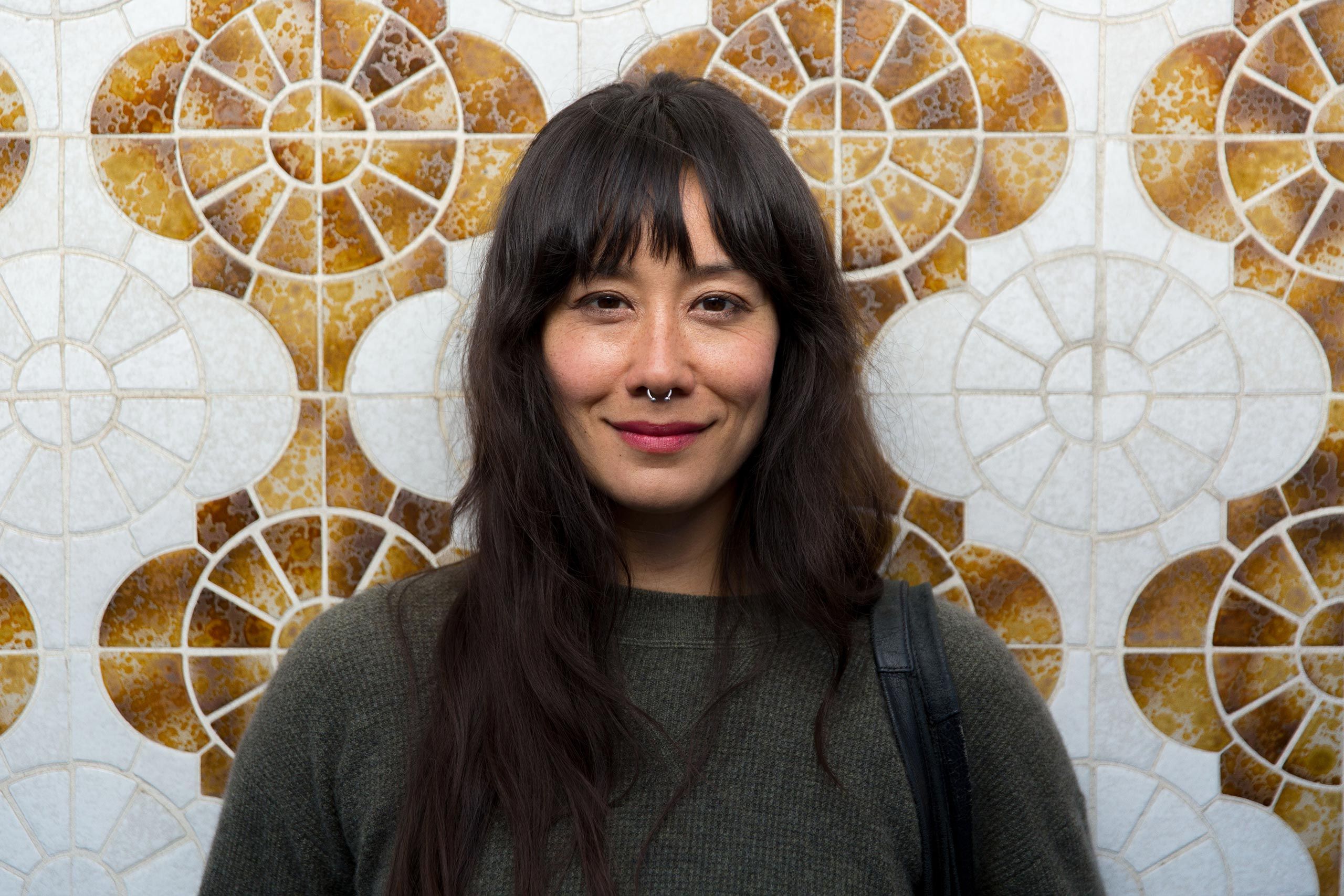 Woman Smiling in Front of a Tiled Wall