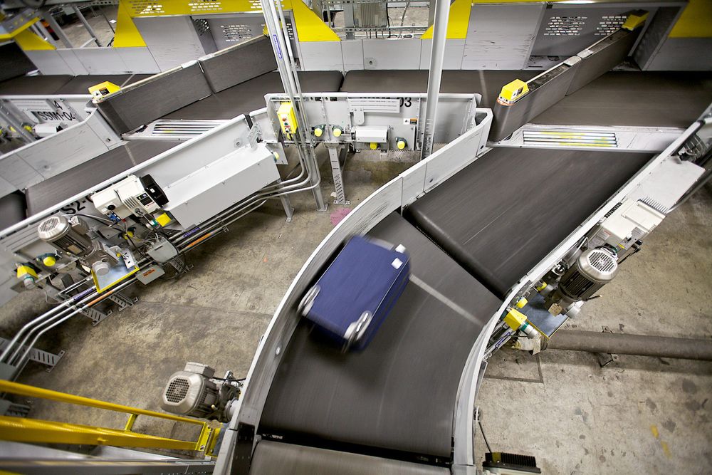 Luggage from an airline passenger on a conveyor system as it moves the bags form ticketing, to the plane. Terminal 1, Designed by Minoru Yamasaki. STL St. Louis Lambert International Airport FLYSTL Environmental portrait, and we are a industrial photographer, on location photographer & location commercial photographer. Luggage on a Conveyor Belt
