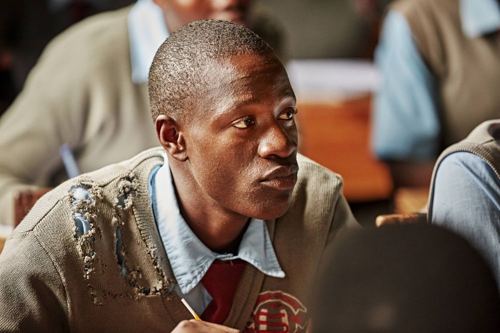 Boy in class listening intently with ripped school uniform sweater. MaleInClass.jpg