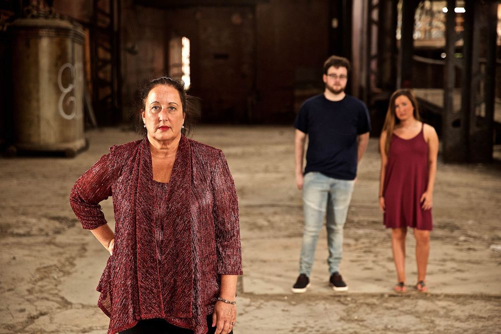 A environmental portrait of a woman who's life was affected by drug use, with her kids slightly out of focus in the background. Photographed in an urban, vacant building in St. Louis. Photographed for a United Way advertising campaign. I am a advertising photographer, on location photographer & location commercial photographer. Photo of one of the many people that the United Way is assisting. Wide angle. Environmental Portrait of a Woman in Vacant Building