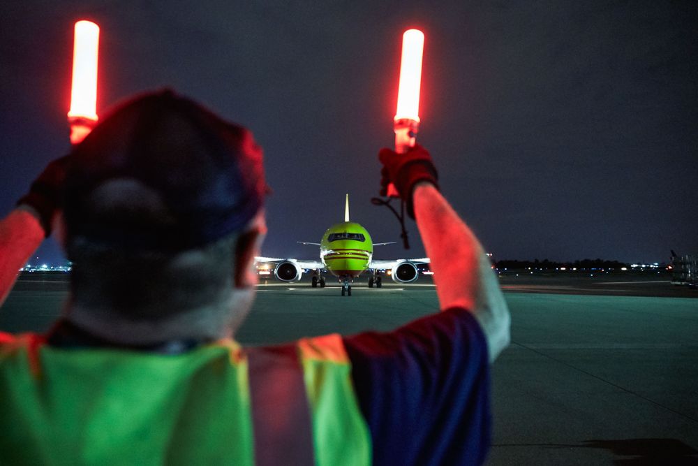 Air Marshaling a DHL Jet to the Runway For Takeoff. The air Marshal is wearing a protective vest and shot from behind as he guides the aircraft with his two red safety wands. Next stop, the other side of the world! This was a project shooting for the air cargo transportation industry. This project was amazing as an industrial photographer, on location photographer & location commercial photographer. Air Marshaling a DHL Jet to the Runway For Takeoff