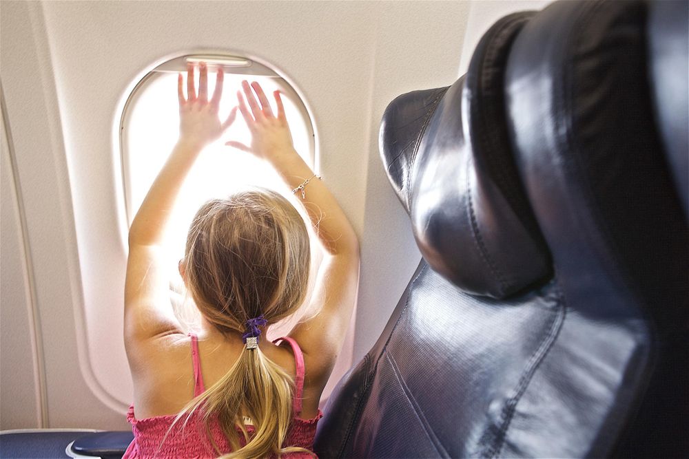 A young girl looking out of a window in a British Airways Boeing 747 plane, in amazement while flying to London. She said, "London looks like a lot of doll houses" Girl Looking out of a Window in a Plane