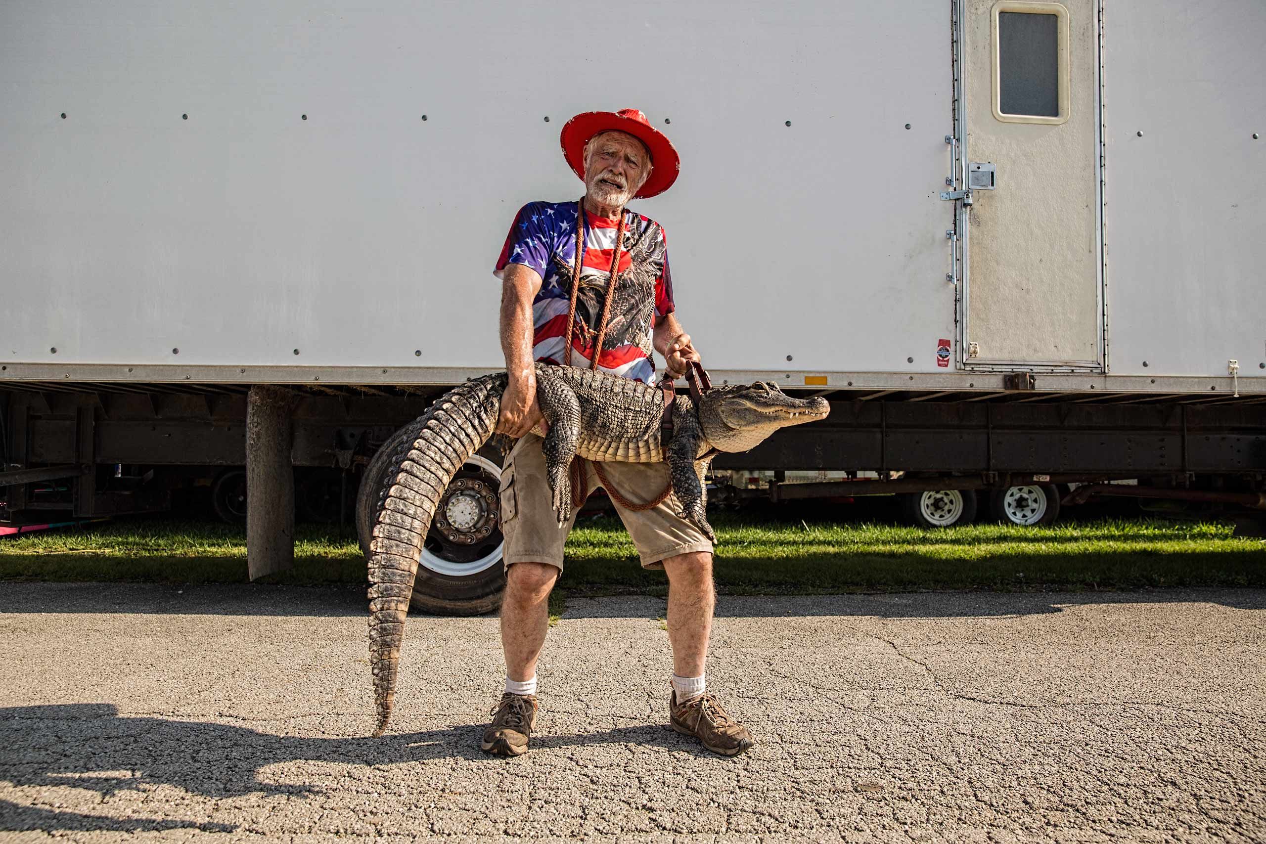 Man Dressed in Red White & Blue Holding an Alligator