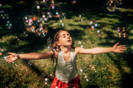 A girl loving the sun and bubbles, day dreaming, in her own world. Girl with Bubbles