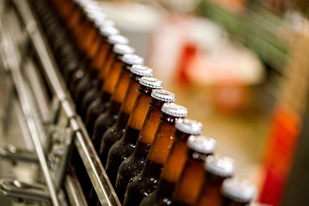 Select focus with shallow depth of field of an assembly line of beer, shot with motion blur. Shot at Schlafly Beer in St. Louis for an advertising campaign and image brand library. As an industrial photographer, on location photographer & location commercial photographer this was a great project to be associated with. Line of Moving Bottles of Beer