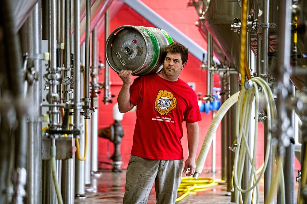 Photo of a brew master holding a keg of beer over his should looking into the camera at Schlafly Beer in St. Louis for an advertising campaign and image brand library. As an industrial photographer, on location photographer & location commercial photographer this was a great project to be associated with. Brewmaster Holding a Keg of Beer