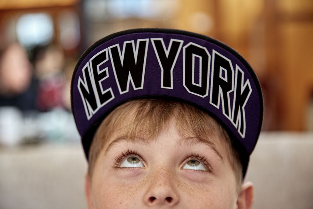 A boy looking up under the brim of his hat that says New York.
Boy With New York Hat 6J0A9240.jpg