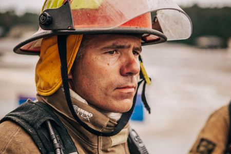 A fireman looks out into the distance, ready to train and action. Photo of Loss Control person dressed in protective fire gear, training and ready for action and to respond and mitigate a disaster as it relates to risk management in the insurance industry. Environmental portrait, and we are a industrial photographer, on location photographer & location commercial photographer. Fireman Ready For Action