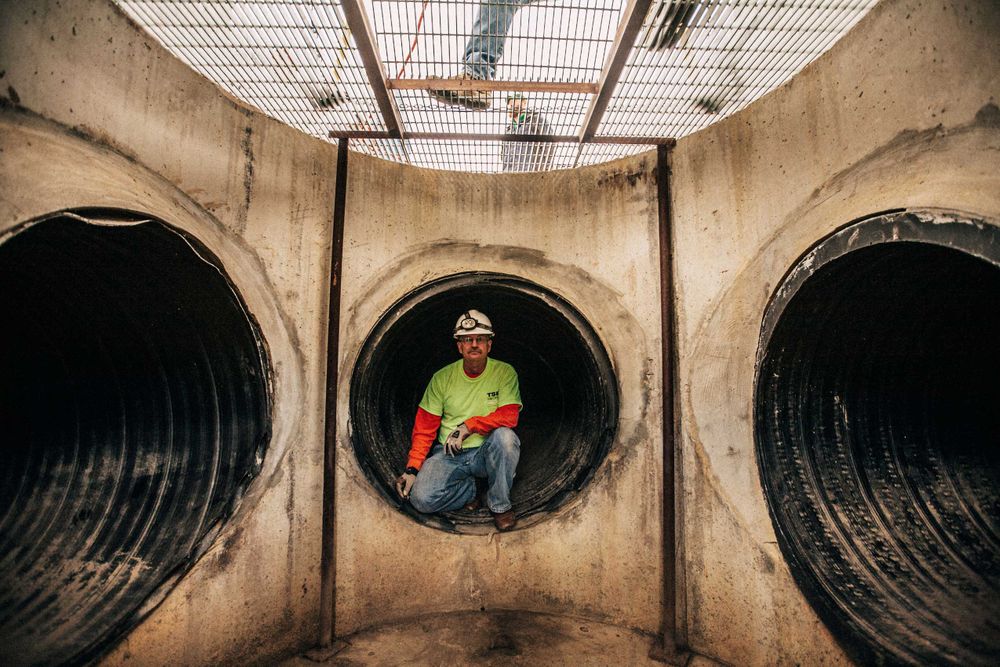 A man who is training to rescue people in a tunnel looks into the camera below ground. Photo of Loss Control person dressed in protective fire gear, training and ready for action and to respond and mitigate a disaster as it relates to risk management in the insurance industry. Environmental portrait, and we are a industrial photographer, on location photographer & location commercial photographer. Rescuer In Tunnel