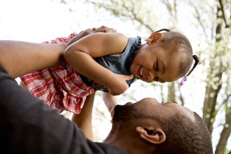 Father holding little girl in the air smiling & happy. Father Holding Up Daughter